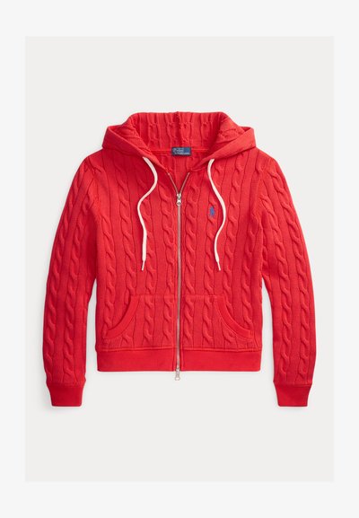Rode kabelgebreide hoodie met ritssluiting, witte trekkoorden, voorzakken, geribbelde manchetten en een klein blauw geborduurd logo op de borst.