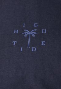 Navyblå bomullstyg med en slät yta som har texten "HIGH TIDE" och en grafisk palmträd i ljusblått centrerad på tyget.