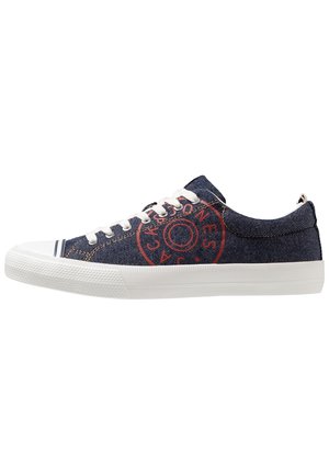Marineblaue Denim-Sneaker mit niedrigem Schnitt, weißer Gummisohle, weißen Schnürsenkeln und rundem roten Logo an der Seite.
