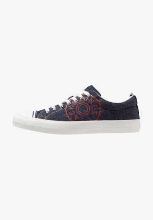 Sneakers in denim blu navy con suola in gomma bianca, lacci bianchi e logo circolare rosso sul lato.