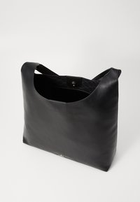 Black leather tote bag with smooth texture, open top, and a secure snap closure. Interior features a patterned lining. Minimalist design.