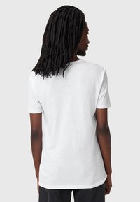 T-shirt bianco a maniche corte con vestibilità rilassata e scollatura rotonda. Tessuto morbido e leggero con una consistenza liscia. Nessun motivo o grafica visibile.