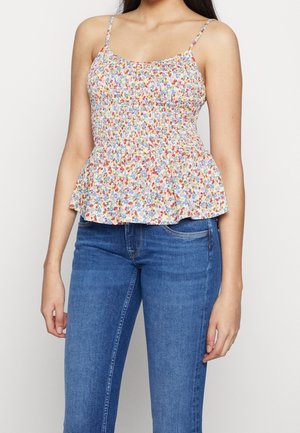 Blomstret peplum-top med justerbare tynde stropper, prydet med en smocket buste i pastelfarver og en flagrende kant. Båret med tætsiddende blå jeans.