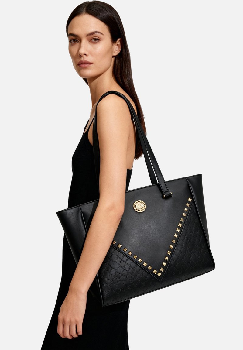 Borsa tote nera con fondo testurizzato, dettagli dorati e motivo triangolare borchiato. Realizzata in materiale sintetico con due manici lunghi.
