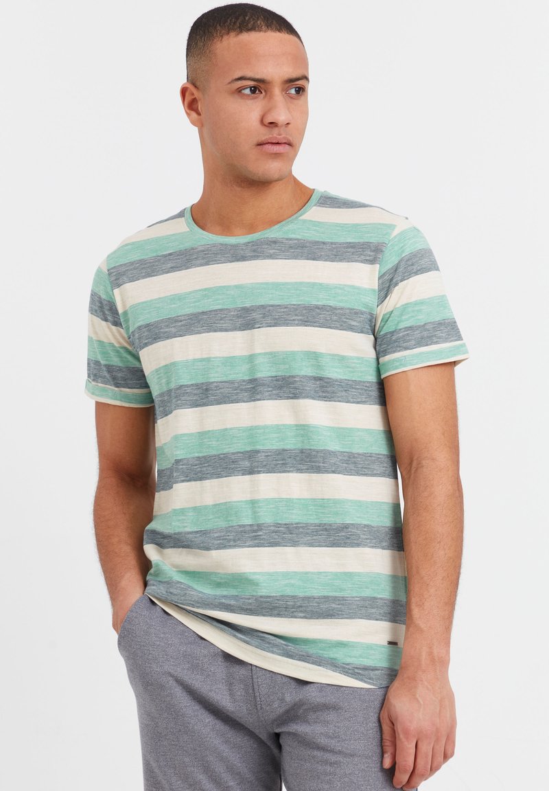 Stripet crew neck t-skjorte med vekslende lysegrønne, mørkegrønne, grå og kremfargede striper. Laget av myk stoff, med korte ermer.