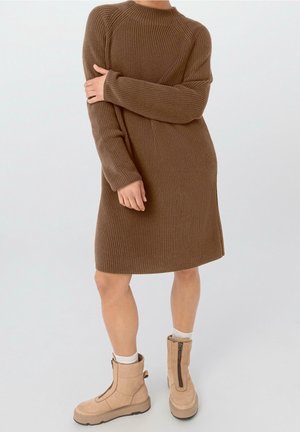 Bruine geribbelde gebreide jurk met lange mouwen en een ronde halslijn, gecombineerd met beige enkellaarsjes met ritsen en gestructureerde zolen.