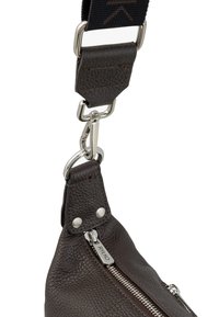 Dark brown leather bag detail featuring a silver zipper, hardware accents, and a textured surface. Includes a detachable strap with a fabric section.