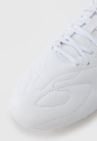 Hvit fotballsko med glatt lærmateriale, teksturerte detaljer, perforeringer og hvite lisser. Buet design med subtil søm.