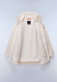 Casaco bege com um exterior felpudo e forro interior suave, apresentando fechos de pressão e um pequeno rótulo da marca no colarinho interior.