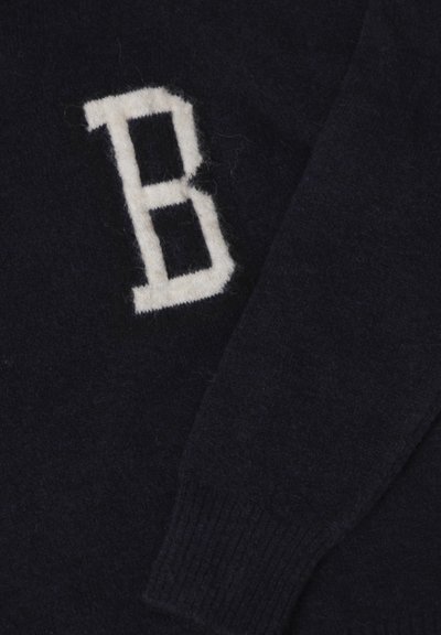 Donkerblauwe trui van zacht, gestructureerd materiaal. Bevat een opvallende, witte, gebreide "B" op de voorkant. Geribbelde mouwen en onderrand.
