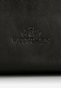 Černá kožená taška s texturovaným povrchem a vyraženým logem. Design je minimalistický, zaměřující se na kvalitní řemeslné zpracování.