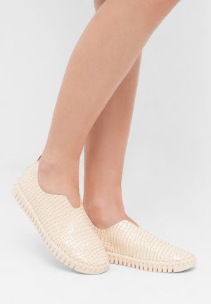 Beige instap schoenen met een reliëfstructuur, ronde neus en rubberen zool met horizontale groeven voor grip.