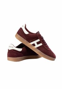 Burgundowe zamszowe sneakersy z białymi akcentami, z gumową podeszwą i teksturowanym wzorem. Logo na pięcie i boku, klasyczny styl sznurowany.