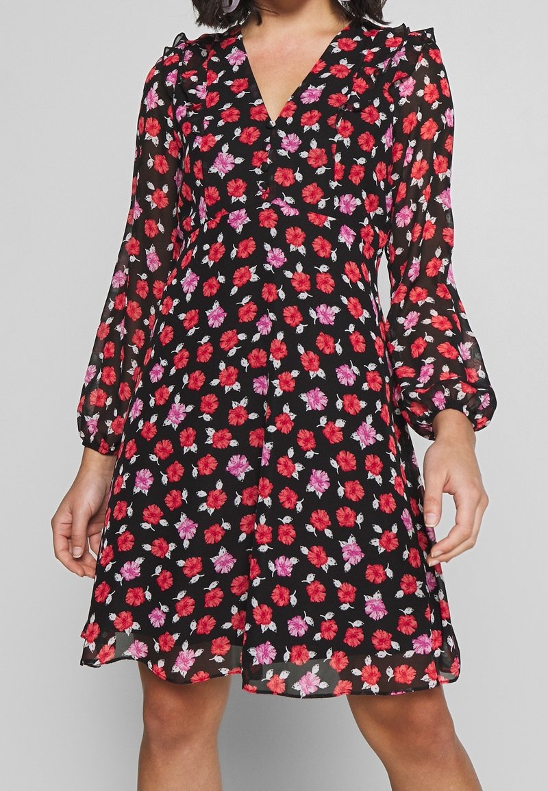 Robe florale noire avec des fleurs rouges et roses, manches longues transparentes, encolure en V et détails à volants aux épaules. Tissu fluide.