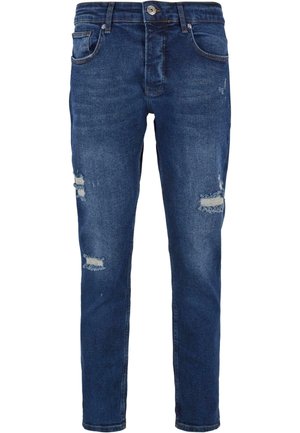 Šauri, tumši zili džinsu bikses ar nolietojumiem un mazu izbalēšanu, ar piecām kabatām un rāvējslēdzēja aizdari ar pogas aizdari.