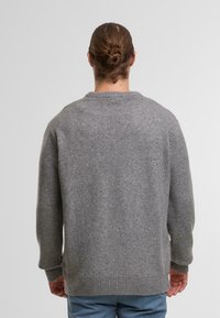 Maglione grigio lavorato a maglia con orlo e polsini a coste, vestibilità comoda e scollo rotondo. La trama appare morbida e calda.