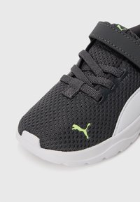 Baskets en mesh noires avec semelle blanche, lacets noirs, bande noire et petit logo Puma vert sur le côté avant.