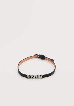 Fekete bőr nyakpánt állítható csattal és ezüstszínű strasszkövekből álló "MOSCHINO" felirattal az elején.