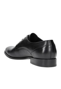 Scarpa da cerimonia nera in pelle con superficie liscia, punta arrotondata, tacco basso e cuciture decorative lungo i lati.