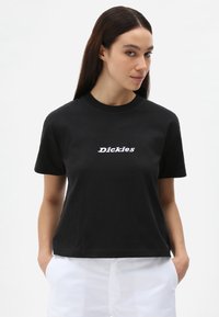 Svart bomull T-skjorte med korte ermer og rund hals, med hvit brodert tekst "Dickies" på forsiden. Glatt tekstur.