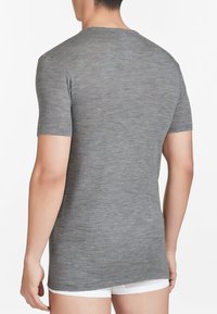 T-shirt grigio a maniche corte realizzato in tessuto leggero, con collo rotondo e un orlo posteriore leggermente più lungo. Texture liscia con un motivo melangiato.