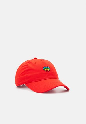 Red cotton baseball cap features a multicolored heart embroidery. It has a curved brim and adjustable strap at the back.