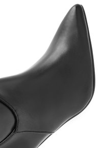 Czarne skórzane botki za kostkę z ostrym noskiem, o smukłym kształcie, gładkiej fakturze i minimalistycznym designie. Zawierają subtelne akcenty w postaci przeszyć.