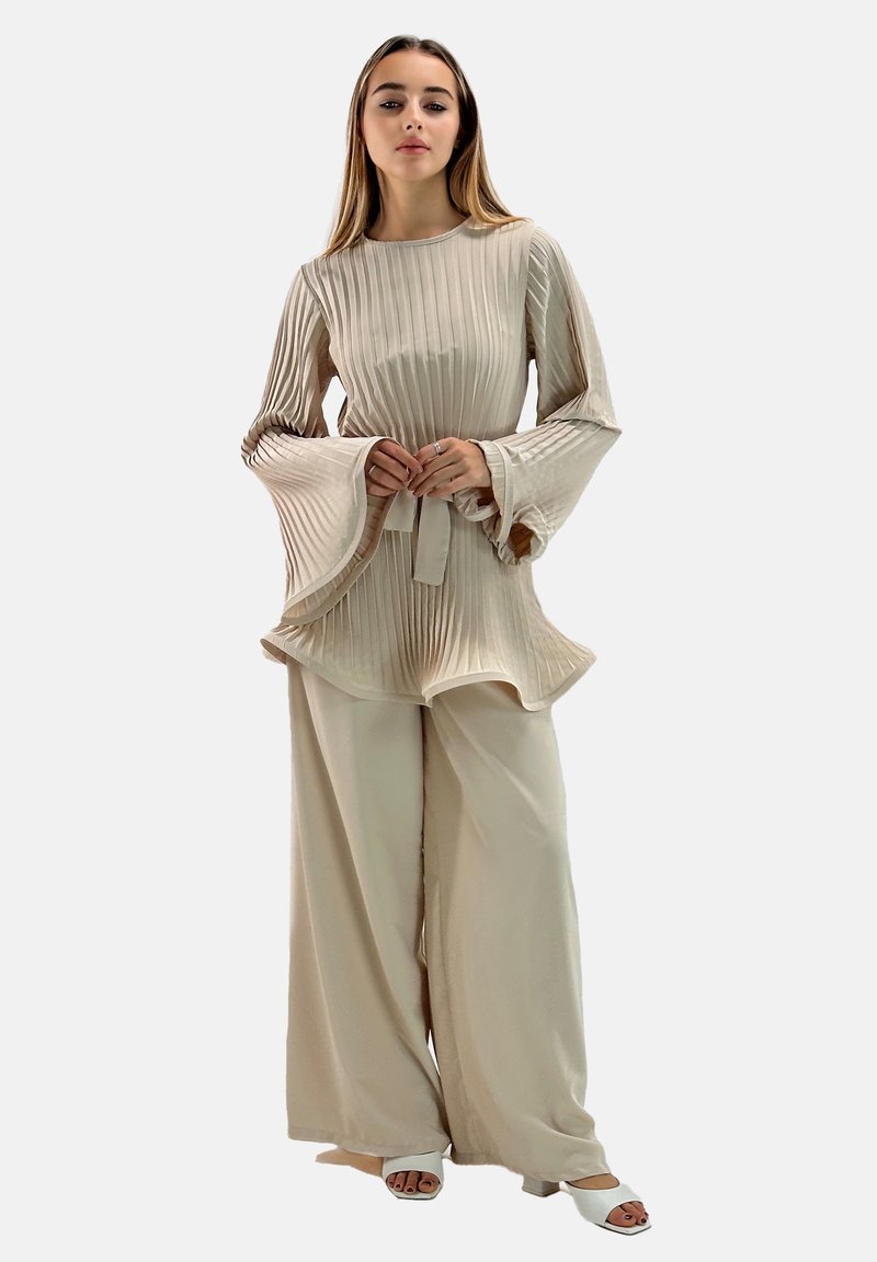 Top plisado beige con mangas acampanadas, combinado con pantalones de pierna ancha en un tono a juego. Tejido suave y liso con un diseño fluido.
