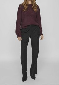 Stickad burgundy tröja med ett strukturerat mönster, tillsammans med svarta byxor. Outfits inkluderar mjukt tyg och tapered byxdesign.