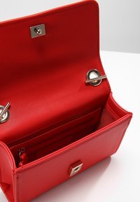 Borsa a mano in pelle sintetica rossa, forma rettangolare strutturata, interno testurizzato, dettagli in metallo dorato, chiusura magnetica e tasche interne multiple.