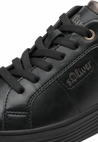 Sneaker in pelle nera con design a lacci, superficie testurizzata, punta arrotondata e suola in gomma. Presenta un piccolo logo e dettagli metallici.
