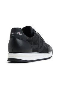 Scarpa da ginnastica nera con parte superiore in pelle liscia e tessuto, suola intermedia bianca e dettagli argentati nel tallone con logo.