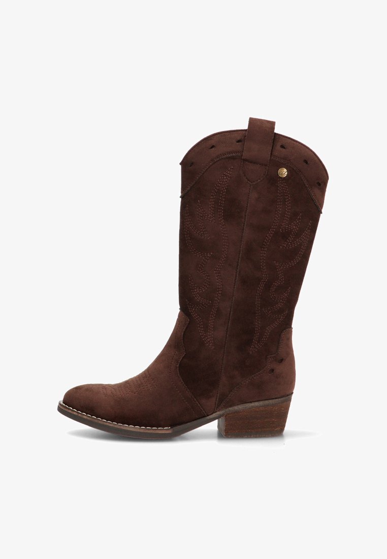 Bota vaquera de ante marrón con costuras decorativas, tacón medio apilado y lengüeta en la parte superior del caño.