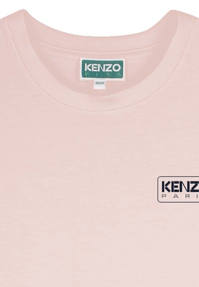 T-shirt rose clair en tissu doux. Présente un col rond et un logo imprimé "KENZO PARIS" en bleu foncé à l'avant.