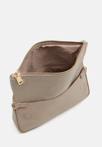Borsa in pelle beige con una cerniera dorata, forma arrotondata e dettagli cuciti. L'interno presenta una fodera liscia con apertura superiore.
