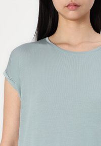 Lyseblå kortærmet bluse med rund halsudskæring. Stoffet er glat og har en subtil ribbet tekstur samt opsmøgte ærmer.