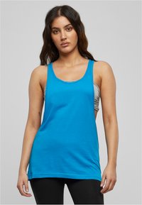 Un vivace top in cotone blu, con scollo rotondo e spalline larghe, dal taglio rilassato che scende oltre i fianchi.