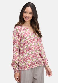 Langärmlige Bluse mit einem auffälligen geometrischen Muster in Rosa, Gelb und Grün. V-Ausschnitt-Design mit gerüschten Bündchen und leichtem Stoff.