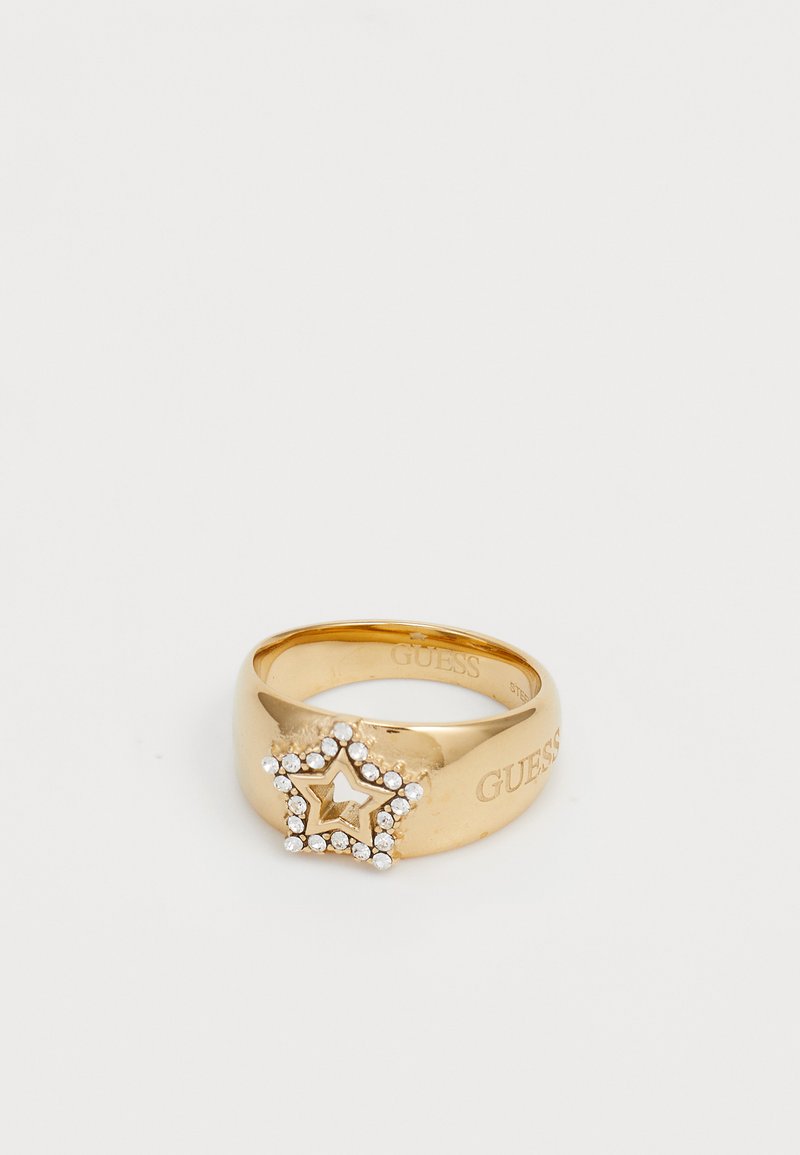 Gouden ring met een stervormig ontwerp dat is voorzien van heldere edelstenen. Gegraveerd met "GUESS" op de band. Glad, glanzend afwerking.