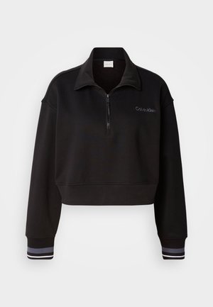 Sweatshirt noir coupé avec un col haut zippé, arborant le logo Calvin Klein et des poignets rayés en blanc et gris. Fabriqué dans un matériau doux.