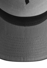 Grauer Bucket-Hat mit einem schwarzen inneren Schweißband, sichtbarer Naht am Rand und einem Mesh-Oberteil zur Belüftung.