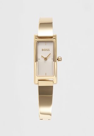 Rektangulært armbåndsur i guldfarve med minimalistisk urskive, BOSS-logo og slankt metalarmbånd.