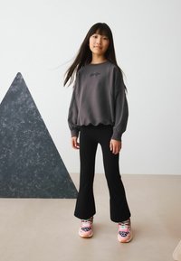 Grå sweatshirt med puffärmar och broderad text, kombinerad med svarta utsvängda byxor och rosa skor med leopardmönster.