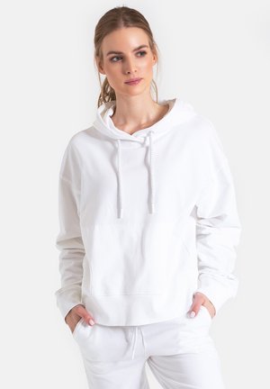 Biała bluza z kapturem wykonana z miękkiego materiału, z dużą kieszenią z przodu, sznurowanym kapturem i luźnym krojem. Teksturowane mankiety i dół. Prosty design.