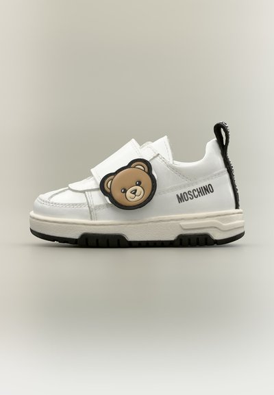 Λευκό παιδικό αθλητικό παπούτσι Moschino με μαύρη σόλα και καρτουνίστικο πρόσωπο αρκούδας στη πλαϊνή λωρίδα.