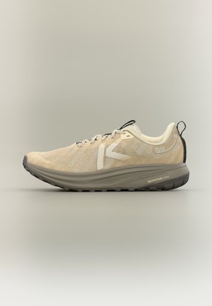 Chaussure de sport beige avec texture tricotée, lacets, semelle épaisse gris foncé estampillée Quantum Foam, et languette noire au talon sur fond neutre.