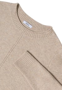 Beige pletený svetr s žebrovaným kulatým výstřihem, manžetami a malou náprsní kapsou. Na etiketě je nápis "CECIL." Měkká textura a bezšvový design.