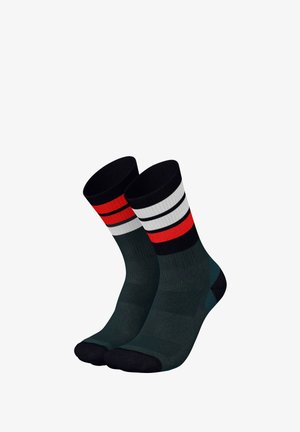 Dunkelgrüne Socken mit schwarz-weißen Streifen am oberen Rand, akzentuiert durch Rot. Ripptextur mit verstärktem Fersen- und Zehenbereich.