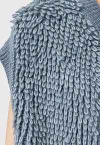 Indumento grigio lavorato a maglia con un design testurizzato e ad anello. Il tessuto morbido crea una ricca qualità tattile con una silhouette rilassata.