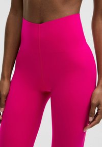 Magas derekú, élénk rózsaszín leggings, rugalmas anyagból készült. Simaság jellemzi, finom varrási részletekkel az oldalán.